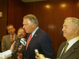 Governor McAuliffe speaks to reporters as budget committee members look on. 