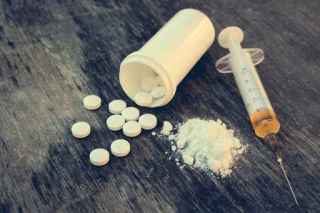 drug addiction on the old wooden background. White pill, syringe